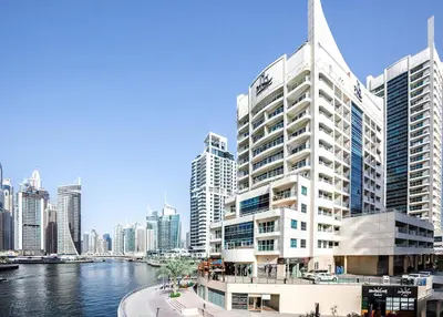 a tall white building next to a river at Canal View apartment in Marina in Dubai