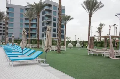 a row of blue lounge chairs with umbrellas and palm trees at a chilled place in Dubai