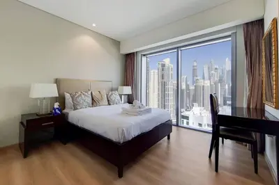 a bedroom with a bed and a desk and a large window at 5-Star Address Dubai Marina Mall Stunning Marina Views 3-Bedroom in Dubai