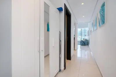 a hallway with white walls and white tile floors at Vacay Lettings - Silverene Marina Retreat - Waterfront Apartment Steps from Marina Mall in Dubai