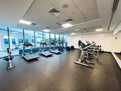 a gym with treadmills and machines in a room with windows at Vacay Lettings - Silverene Marina Retreat - Waterfront Apartment Steps from Marina Mall in Dubai