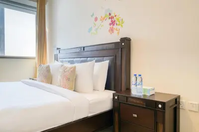 a bed with white pillows and a nightstand with a table at Luxury 1BR Apartment Executive Towers Business Bay in Dubai
