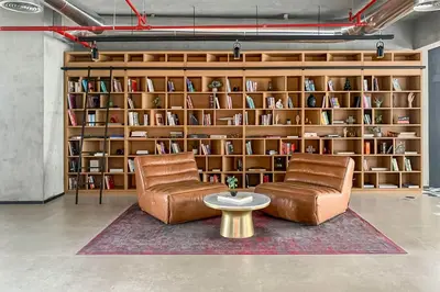 a library with two chairs and a table and bookshelves at Frank Porter - Collective Tower 1 in Dubai