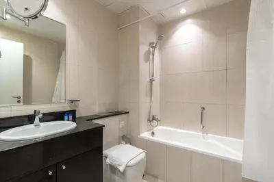 a bathroom with a sink and a tub and a toilet at Vacay lettings - Upgraded studio at Damac tower JVC in Dubai