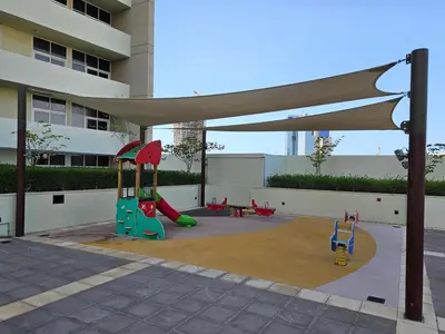 a playground with a slide and play equipment in front of a building at Vacay lettings - Upgraded studio at Damac tower JVC in Dubai
