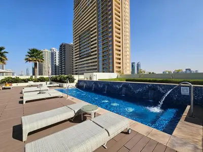 a swimming pool with two benches and a building at Vacay lettings - Upgraded studio at Damac tower JVC in Dubai