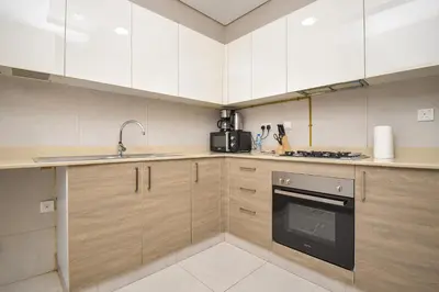 a kitchen with white cabinets and a sink and a stove at Elegant 2BR view with rooftop pool The Bay in Dubai
