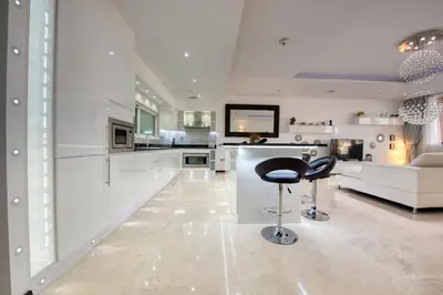 a white kitchen with a bar stool in the middle at Tiara Residence Ruby, Palm Jumeirah - Mint Stay in Dubai