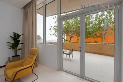 a lobby with a chair and a sliding glass door at Tiara Beach Residences, Palm Jumeirah Dubai - Mint Stay in Dubai