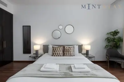 a bedroom with a large white bed with two lamps at Tiara Beach Residences, Palm Jumeirah Dubai - Mint Stay in Dubai