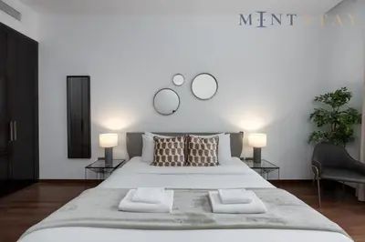 a bedroom with a large white bed with two lamps at Tiara Beach Residences, Palm Jumeirah Dubai - Mint Stay in Dubai
