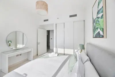 a white bedroom with a bed and a mirror at Free Beach Access! Beautiful Palm Jumeirah & Dubai Eye in Dubai