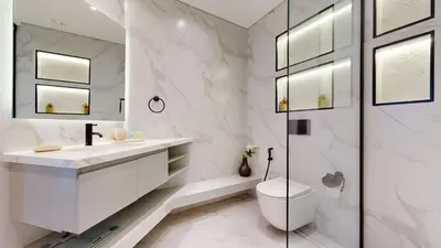 a white bathroom with a toilet and a sink at Vacationer I Glamorous 2 Bedroom I Steps from Barasti Beach I Marina Views in Dubai