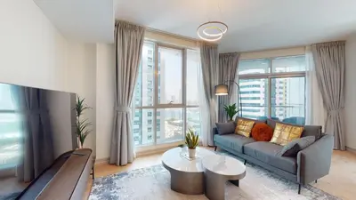 a living room with a couch and large windows at Vacationer I Glamorous 2 Bedroom I Steps from Barasti Beach I Marina Views in Dubai