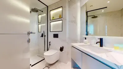 a white bathroom with a toilet and a sink at Vacationer I Glamorous 2 Bedroom I Steps from Barasti Beach I Marina Views in Dubai