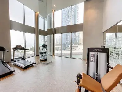 a gym with a treadmill and large windows at 5242 Tower 2 - Light One Bedroom in Dubai