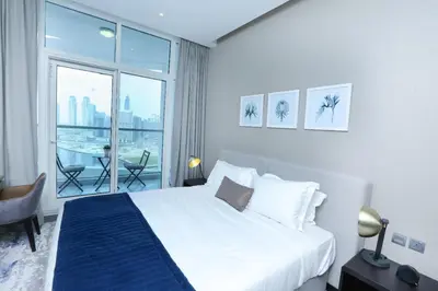 a hotel room with a bed and a large window at DAMAC MAISON PRIVE - Deluxe Studio With Balcony & Water Canal View in Dubai