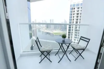 a table and chairs on a balcony with a view of a city at DAMAC MAISON PRIVE - Deluxe Studio With Balcony & Water Canal View in Dubai