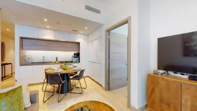 a kitchen and dining room with a table and a television at Stylish Apartment Balcony and Sea Views in Dubai