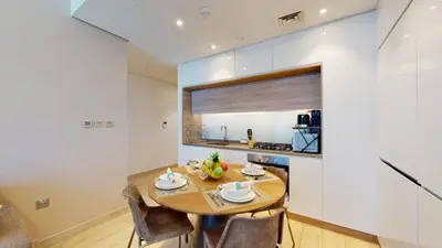 a kitchen and dining room with a wooden table and chairs at Stylish Apartment Balcony and Sea Views in Dubai