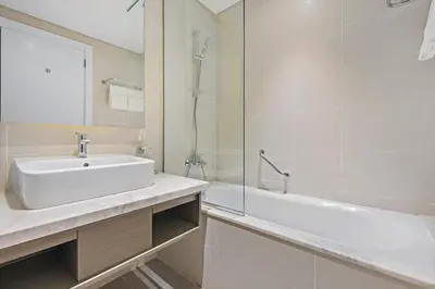 a white bathroom with a sink and a shower at ALiving Luxury Studio I DAMAC Maison Prive A- 1007 in Dubai