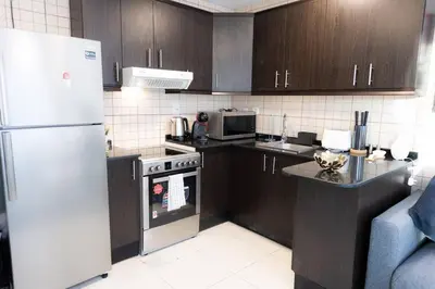 a kitchen with wooden cabinets and a white refrigerator at Royal Oceanic in JBR by HAPPY SEASON in Dubai