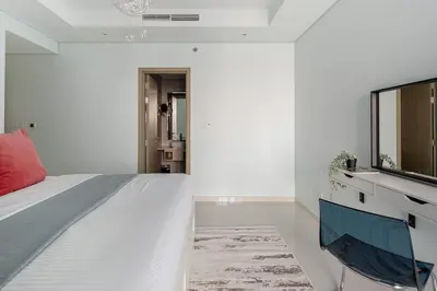a white bedroom with a bed and a television at Frank Porter - Paramount Midtown in Dubai