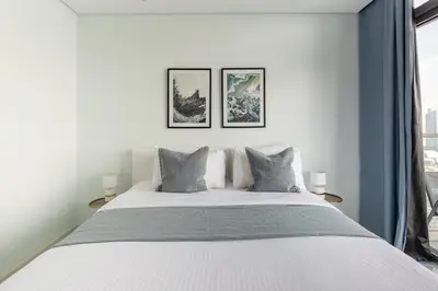 a bedroom with a white bed with three pictures on the wall at Frank Porter - Paramount Midtown in Dubai