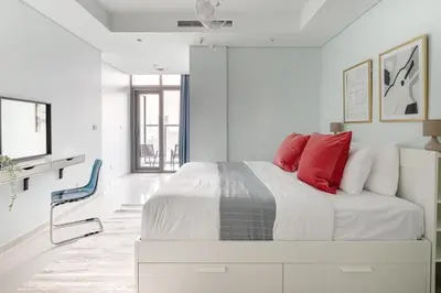 a white bedroom with a bed with red pillows at Frank Porter - Paramount Midtown in Dubai