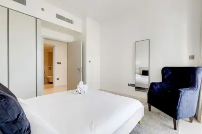 a bedroom with a bed and a blue chair at Sunrise Bay 2 - Chic Two Bedroom in Dubai