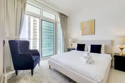 a bedroom with a large bed and a blue chair at Sunrise Bay 2 - Chic Two Bedroom in Dubai