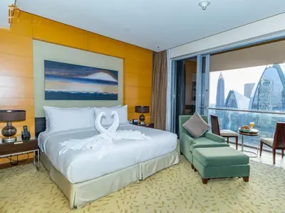 a bedroom with a large bed and a green chair at Paradise View The Dubai Mall Residences in Dubai
