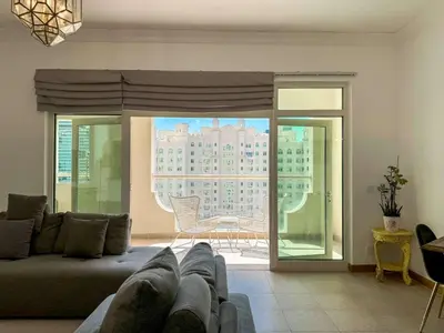 a living room with a couch and a view of a building at Upgraded 2BR apartment at the beach - Shoreline 1 in Dubai