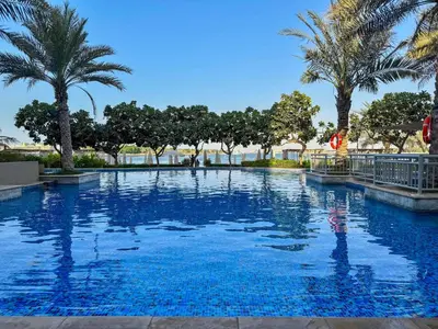 a swimming pool with palm trees in a resort at Upgraded 2BR apartment at the beach - Shoreline 1 in Dubai
