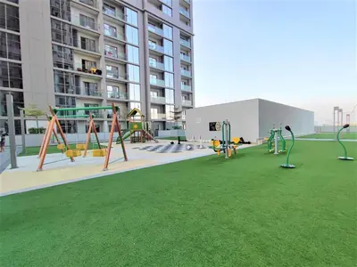 a playground in the middle of a building with green grass at New 2 bedroom in Meydan - Green Area in Dubai