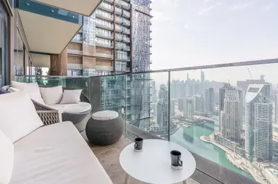 a balcony with white furniture and a view of a city at GuestReady - Luxe Suite in Jumeirah Marina in Dubai