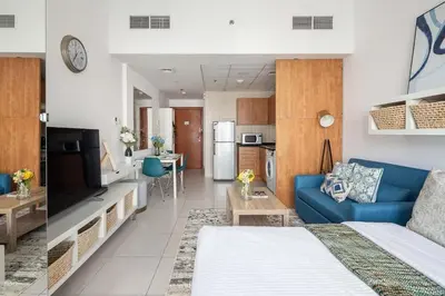 a living room with a blue couch and a kitchen at Frank Porter - Marina Views T1 in Dubai
