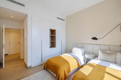 two beds in a room with white walls at 2BR Le Pont B3 Full Sea and Pool View in Dubai