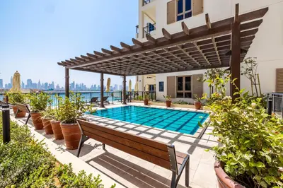 a swimming pool with a pergola and a bench at 2BR Le Pont B3 Full Sea and Pool View in Dubai