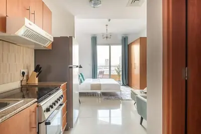 a kitchen with a refrigerator and a room with a bed at Frank Porter - Lakeside Tower D in Dubai