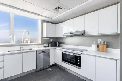 a kitchen with white cabinets and a large window at Ultra Luxe 5BR Al Bateen I Private Beach and Pool I JBR Full Sea View Beachfront in Dubai