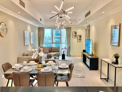 a living room with a dining table and a couch at White Sage - Lakefront Apartment Amidst Parks With Lake Access in Dubai