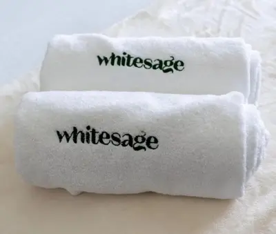 two white towels with the word wilderness written on them at White Sage - Lakefront Apartment Amidst Parks With Lake Access in Dubai