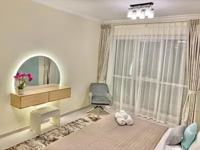 a bedroom with a chair and a bed and a mirror at White Sage - Lakefront Apartment Amidst Parks With Lake Access in Dubai