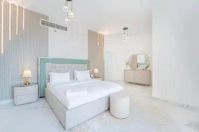 a white bedroom with a large bed and a mirror at JBR - Shams Suites - Sea & Marina View Walking Distance to The Beach by Gardenia in Dubai