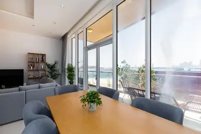 a living room with a table and chairs and windows at Tiara Residences, Palm Jumeirah Dubai - Mint Stay in Dubai