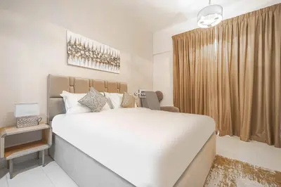 a bedroom with a large white bed and a window at Everluxe Azizi Montrell Lovely Studio in Dubai