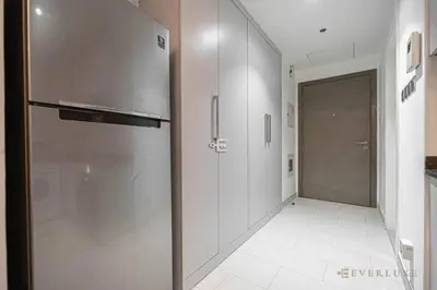 a kitchen with a stainless steel refrigerator and a hallway at Everluxe Azizi Montrell Lovely Studio in Dubai