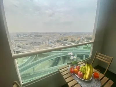 a plate of fruit on a table in front of a window at Manchester Regency - 2BR Apartment in Dubai Marina in Dubai
