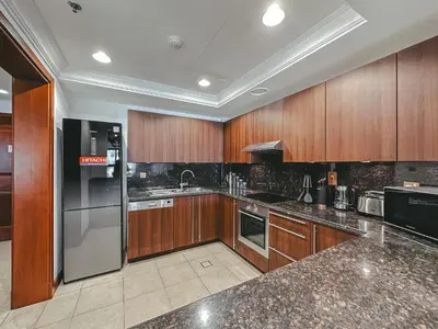 a kitchen with wooden cabinets and stainless steel appliances at Luton Vacation Homes - Luxury & Spacious 1BR North Residence Fairmont , Palm Jumeirah - 90AB3 in Dubai